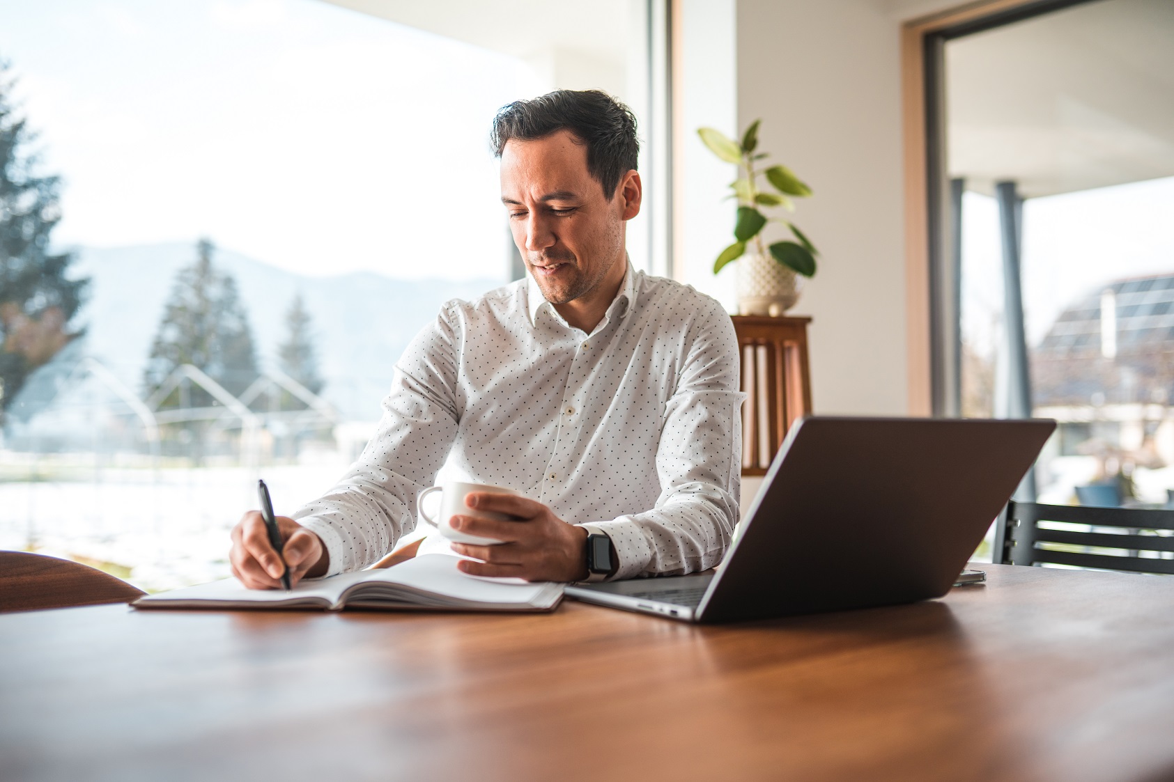 man at desk with coffee and laptop