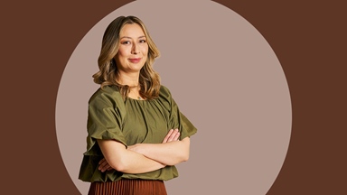 Portrait of a person with folded arms wearing a green top against a circular neutral background.