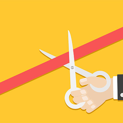 Business person hand with scissors cutting red tape
