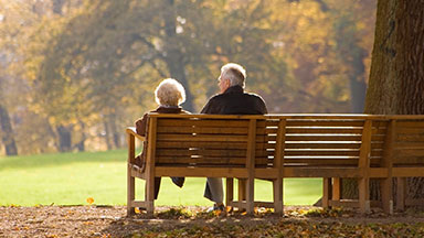 Two elderly people sitting park bench