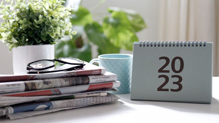 Desk stacked papers, reading glasses and 2023 calendar