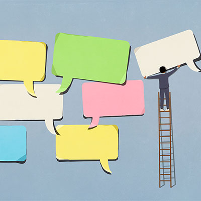 Business person on ladder arranging large, multicolored speech bubbles on blue background