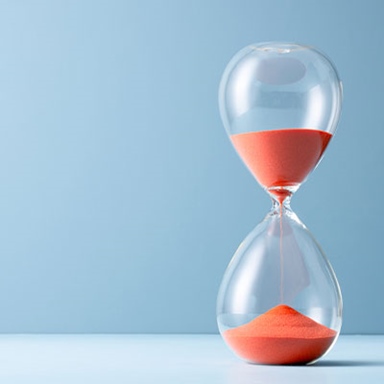 Orange Sand Hourglass on Light Blue Colored Background