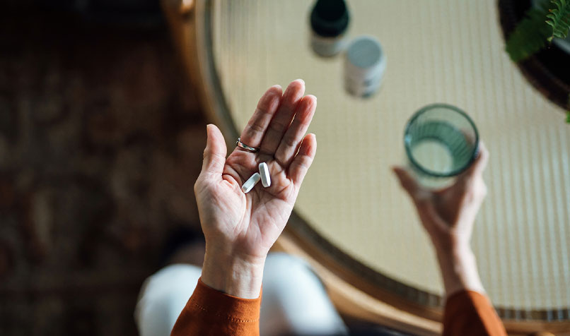 Older hand with medication and glass water