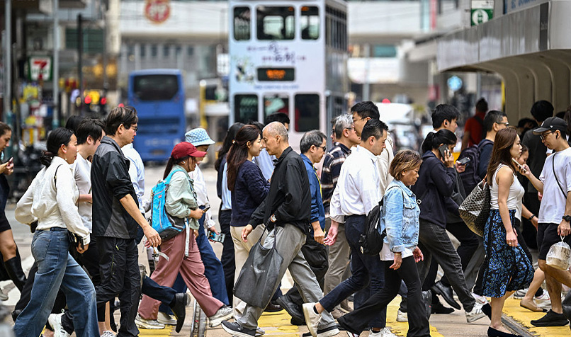 Pedestrians cross a busy intersection in Central business district of Hong Kong.
