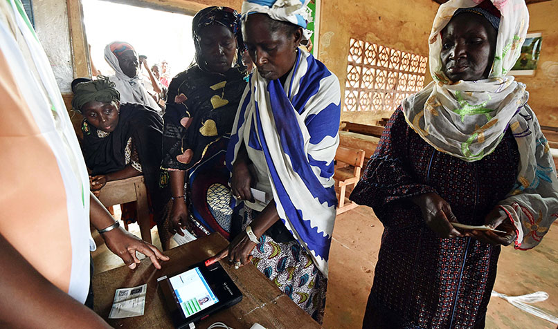 A woman casts her vote using a fingerprint scanner