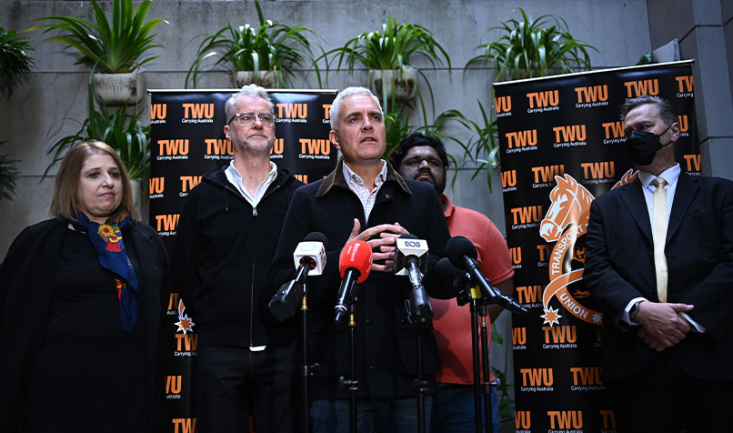 Group of people standing in from of banners holding a press conference