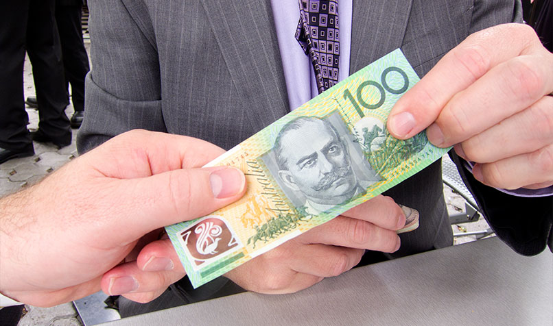 Man in suit taking 100 dollar note from another hand