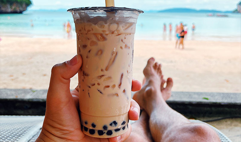 Person holding Chatime drink on beach
