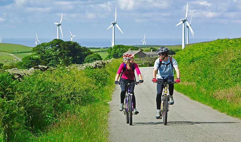 Country side two bike riders wind turbines