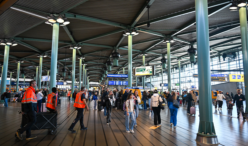 Inside an airport with multiple blue columns and crowds of people
