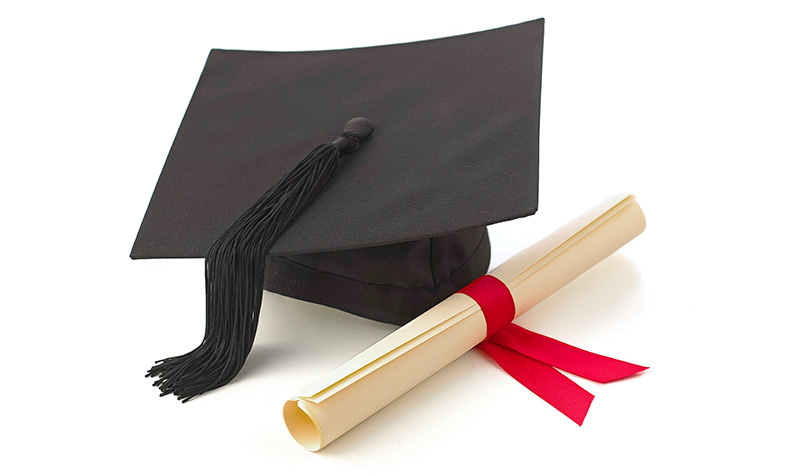 graduation hat and certificate rolled up and tied with red ribbon