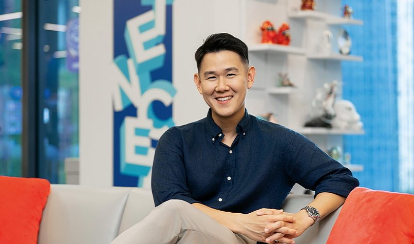 Person seated on a sofa in an office, with shelving and the word “TENCENT” visible in the background.