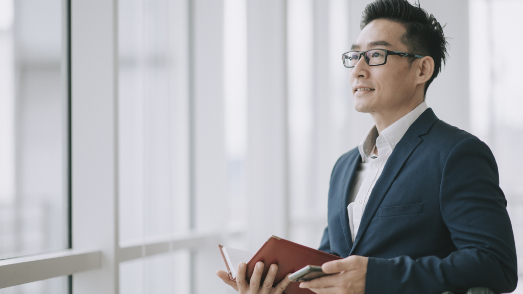 Asian-man-holding-book-in-office
