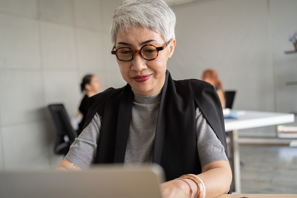 Happy late career woman using laptop