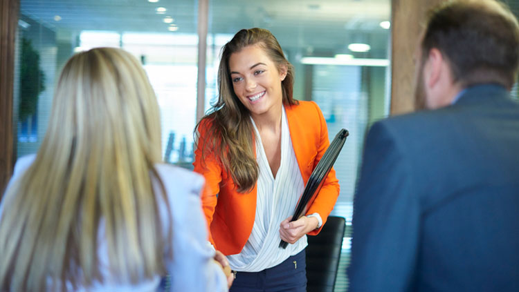Women greeting two people in office