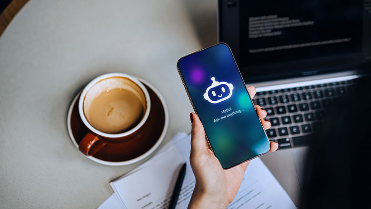 Person working laptop with coffee using AI on phone