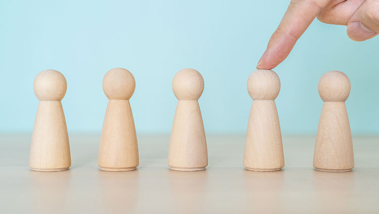 5 wooden people hand selecting one