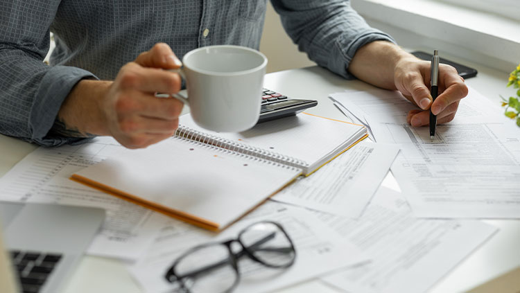 Business person working at desk with documents and cup