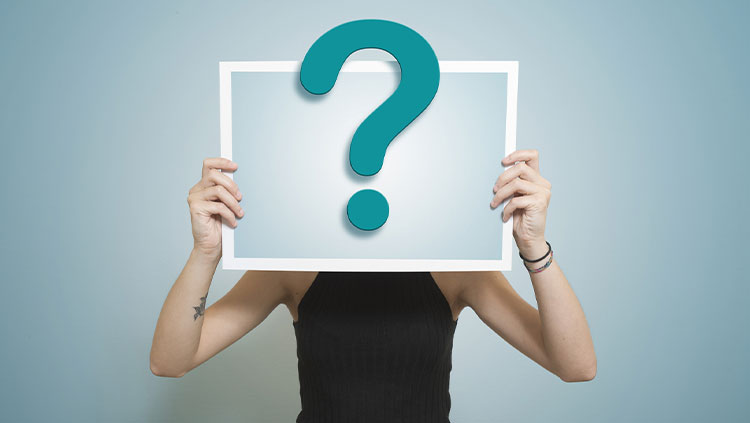 Person holding question mark over face