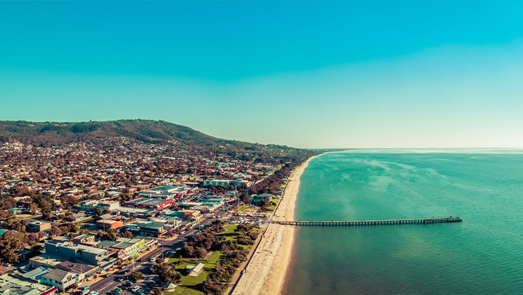 Beachside town with hills in background on a sunny day.