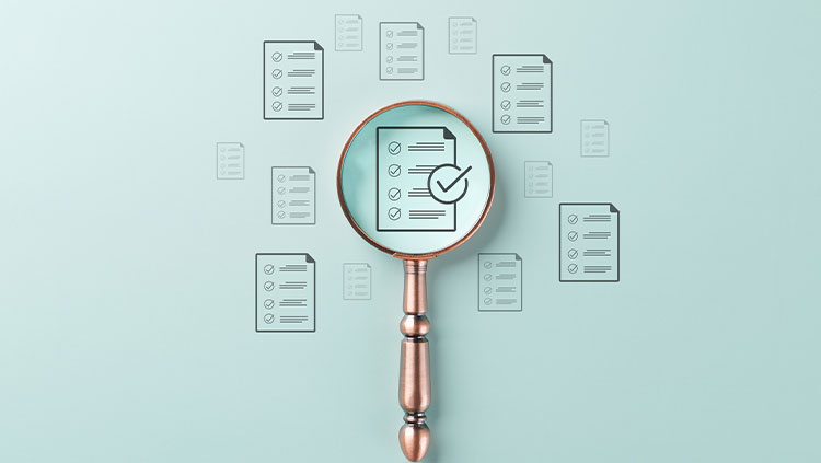 Magnifying glass highlighting a checklist document with a tick, surrounded by multiple documents, representing document review, compliance or quality assurance.