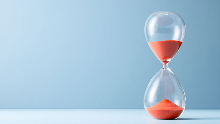 Orange Sand Hourglass on Light Blue Colored Background