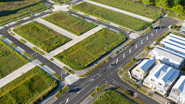 Aerial view of a residential subdivision with roads, intersections and undeveloped housing lots surrounded by greenery.