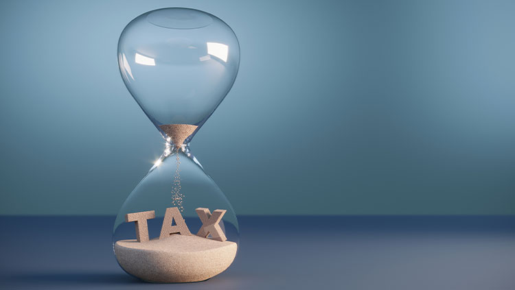 Flowing sand shaped of tax text inside the hourglass