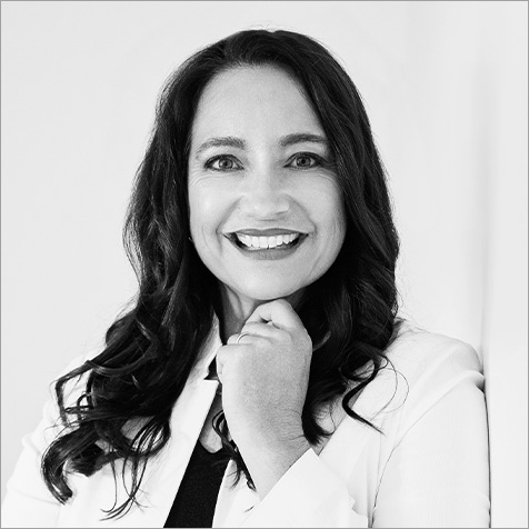 Black and white photo of a women with long dark hair over shoulders wearing a white jacket