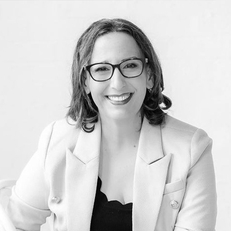 Women wearing glasses and light coloured jacket with medium length brown hair, image is in black and white
