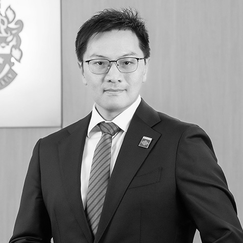 Professional headshot of a person in business attire standing in an office setting