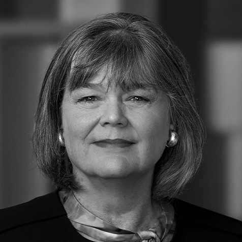 Head-and-shoulders portrait of a person with shoulder-length hair, wearing earrings and a dark jacket.