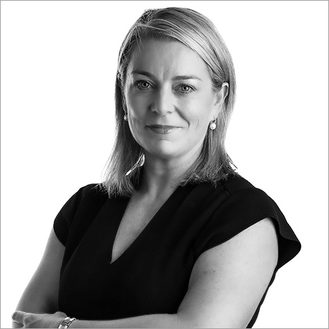 A black and white image of a women with blonde shoulder length hair and black dress with arms crossed