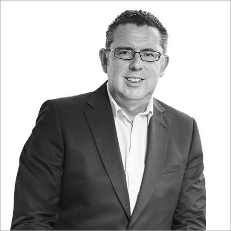 Man with glasses in a shirt and business jacket buttoned up looking at camera