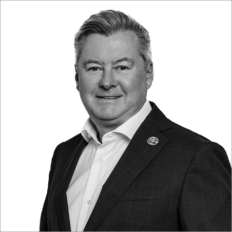 Business person with shirt and jacket on, turned slightly sideways smiling at camera