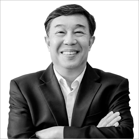 Black-and-white professional headshot of a person wearing a dark business suit jacket over a white collared shirt. The portrait is cropped from the waist upwards against a plain light background, with the subject facing the camera and arms crossed. The simple composition, formal business attire and neutral backdrop create a polished corporate profile image, with the focus on the individual's professional presentation.
