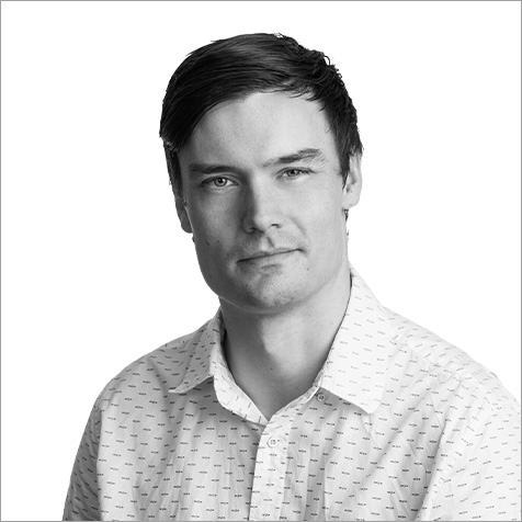 Professional headshot of a person wearing a patterned shirt against a plain background.
