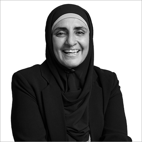Black-and-white portrait of a person wearing a blazer against a plain background.