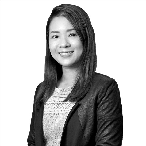Black-and-white head-and-shoulders portrait of a person wearing a blazer over a patterned top against a plain background.