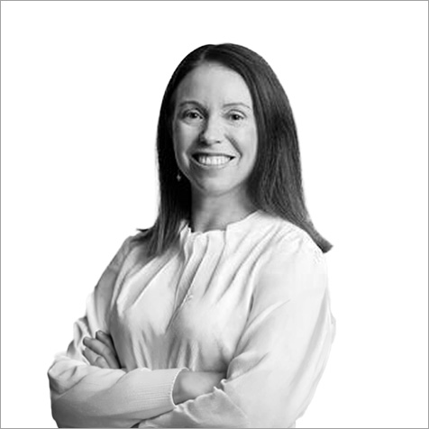 Professional headshot of a person with crossed arms, wearing a light-coloured blouse against a plain background.