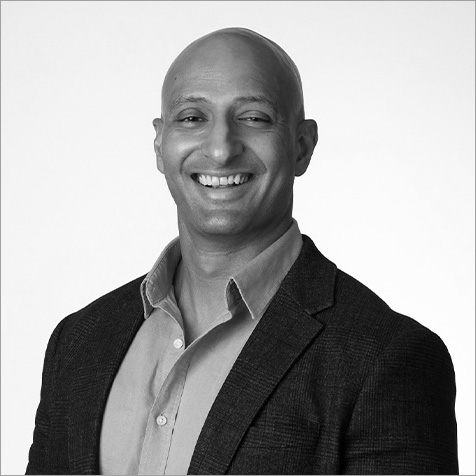Professional headshot of a person wearing a collared shirt and dark blazer, facing the camera against a plain background.